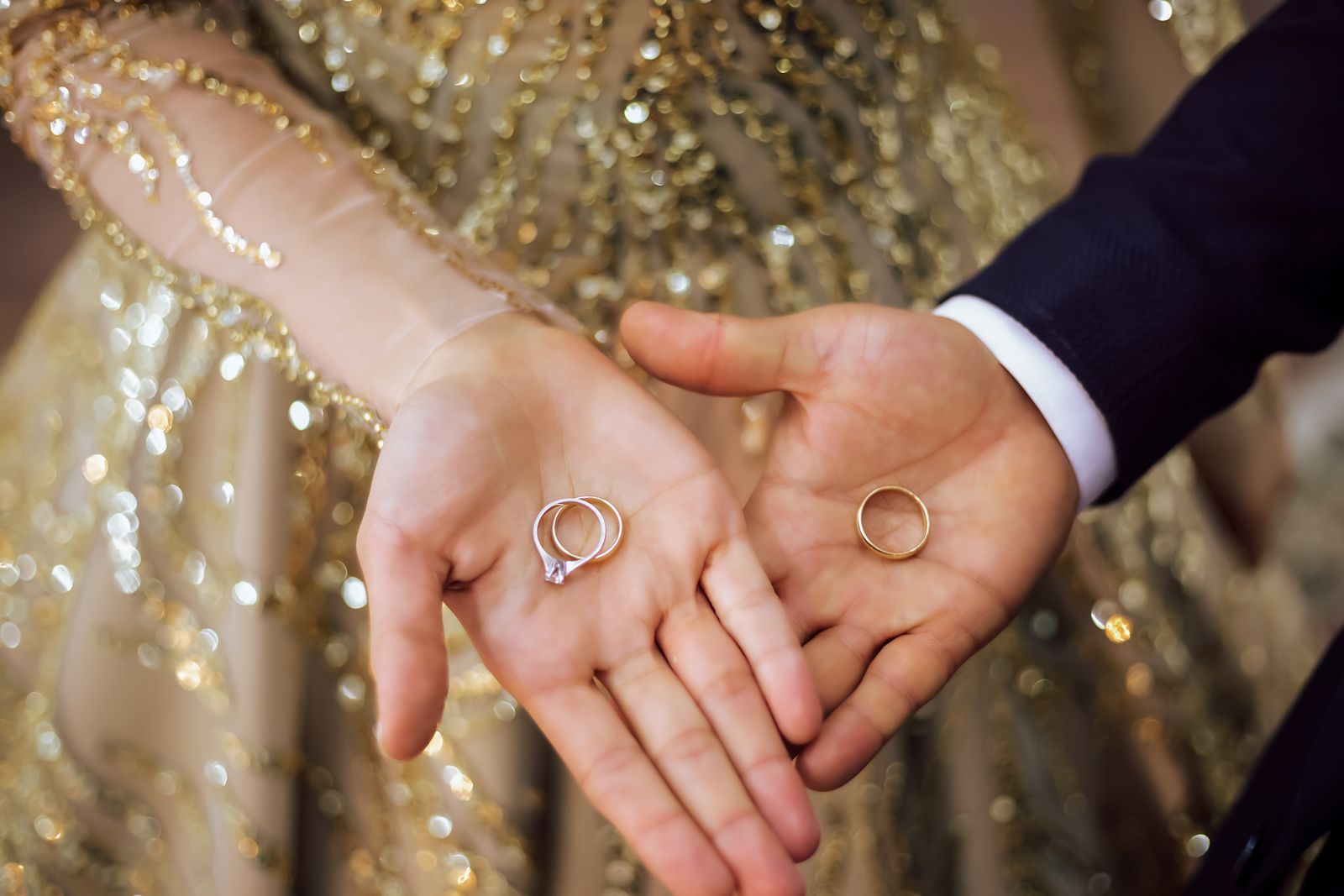 An engaged couple holding their wedding and engagement rings in their open hands